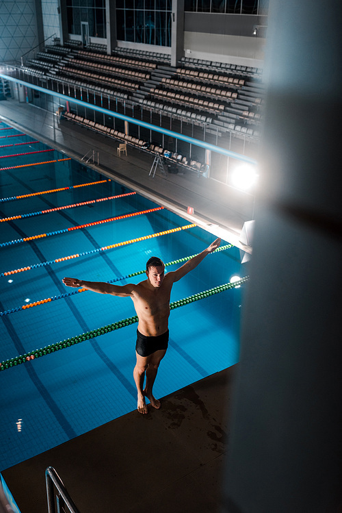 high angle view of swimmer standing with hands above head near swimming pool