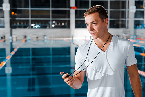 happy trainer holding timer near swimming pool