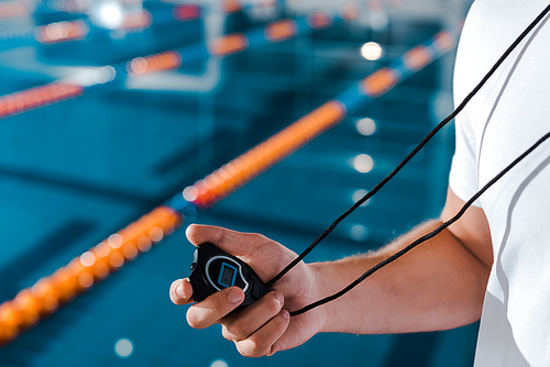 cropped view of trainer holding timer near swimming pool