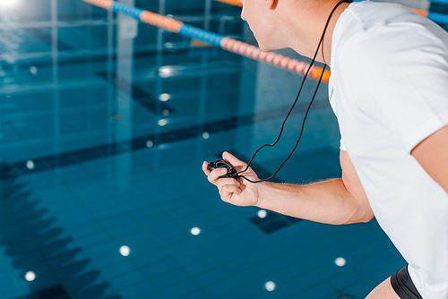 cropped view of athletic trainer holding timer near swimming pool