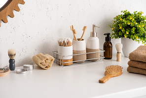Shelf with hygiene objects and beauty products with flowerpot in bathroom, zero waste concept