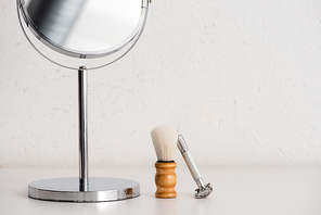 Close up view of round mirror, shaving brush and razor on white background, zero waste concept