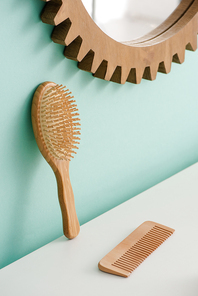 Hairbrush with comb and round mirror on turquoise wall in bathroom, zero waste concept