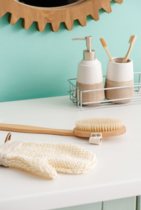 Hygiene products on shelf near massage brush and bath glove in bathroom, zero waste concept