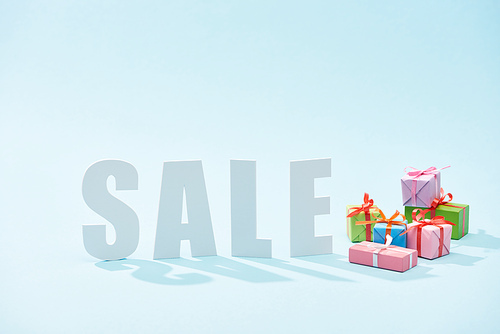 white sale lettering and festive gift boxes on blue background