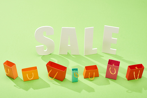 decorative colorful shopping bags and sale lettering on green background