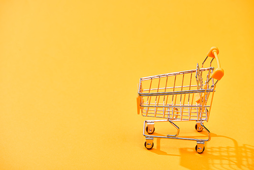 empty decorative shopping cart on bright orange background
