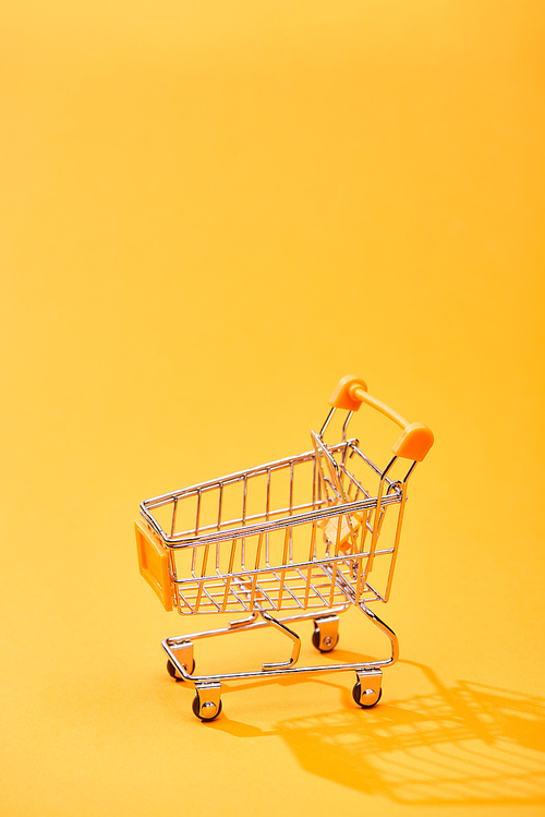empty small shopping cart on bright orange background