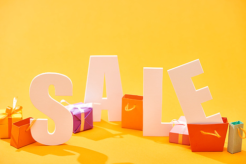 small shopping bags among white sale lettering on orange background
