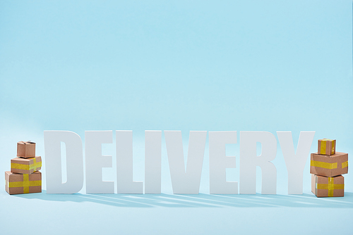 white delivery lettering with shadows near closed cardboard boxes on blue background