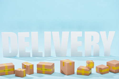 white delivery lettering with shadows behind closed cardboard boxes on blue background