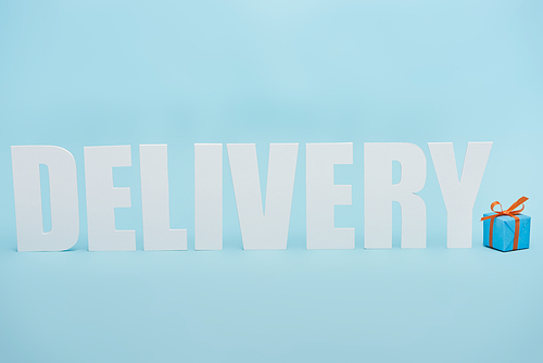 white delivery inscription with shadows near gift box on blue background