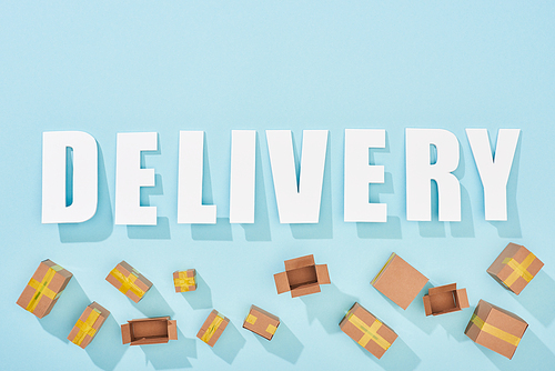 top view of white word delivery near open and closed cardboard boxes on blue background