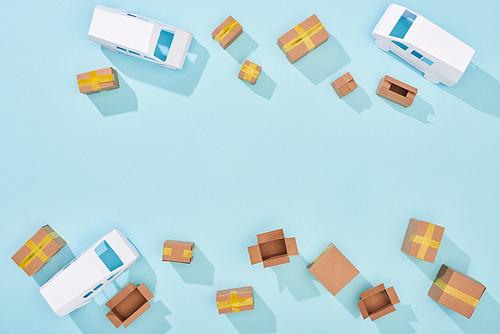 top view of delivery vans models and carton boxes on blue background
