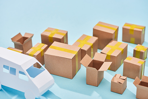 cardboard boxes near van model on blue background with copy space