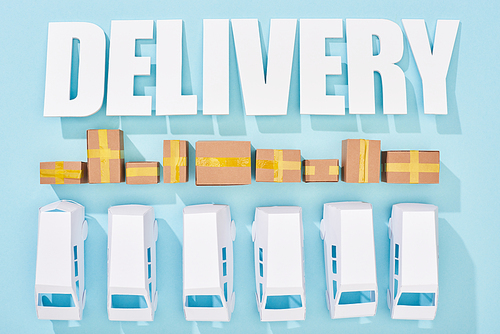 white delivery inscription with shadows over cardboard boxes and mini vans on blue background
