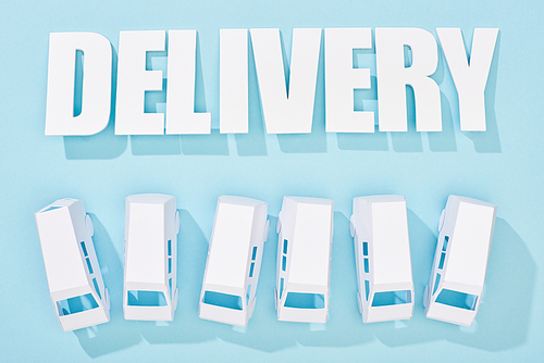 delivery inscription with shadows near mini vans on blue background