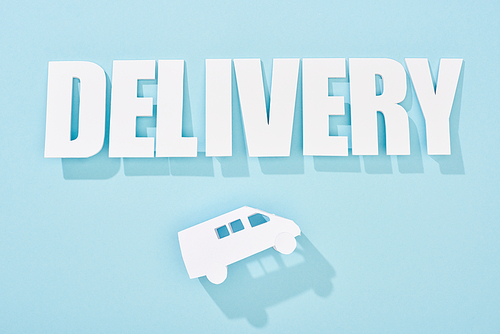 white delivery inscription with shadow above mini van on blue background