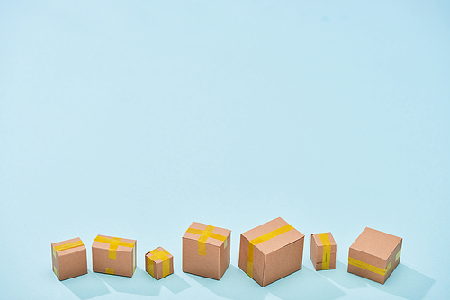 miniature closed cardboard boxes on blue background with copy space