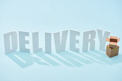 cardboard boxes one on each other near white delivery inscription on blue background