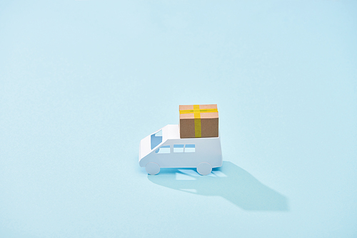 white mini van with cardboard parcel on blue background