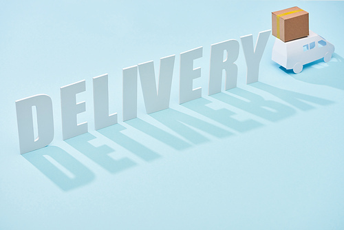 delivery inscription near white mini truck with cardboard box on blue background