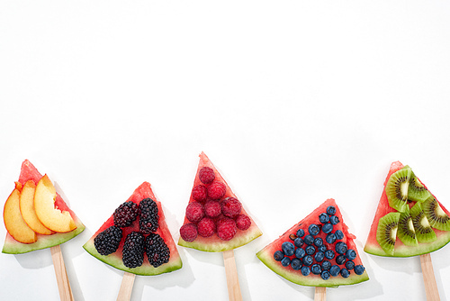 top view of fresh watermelon on sticks with seasonal berries and fruits on white background with copy space