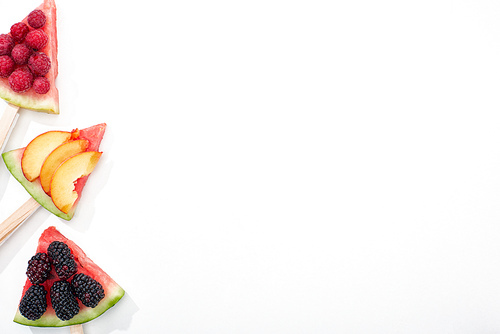 top view of delicious watermelon on sticks with seasonal berries and peach on white background with copy space