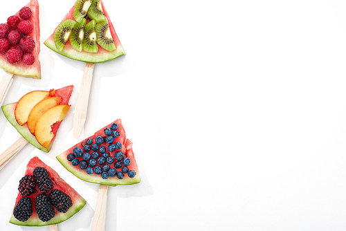 top view of tasty watermelon on sticks with seasonal berries and fruits on white background with copy space
