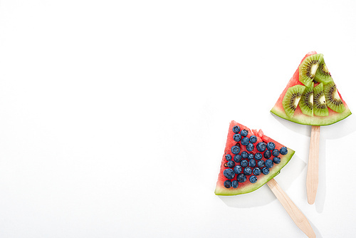 top view of delicious watermelon on sticks with blueberries and kiwi on white background with copy space
