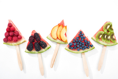 top view of delicious watermelon on sticks with seasonal berries and fruits