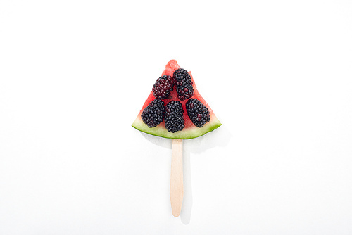 top view of delicious watermelon on stick with blackberries on white background