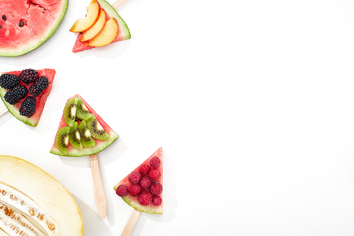 top view of watermelon on sticks with seasonal berries and fruits on white background with copy space