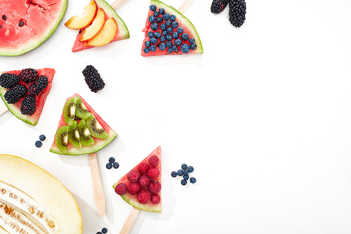 top view of delicious watermelon on sticks with seasonal berries and fruits on white background with copy space