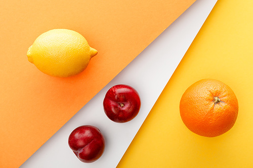 Top view of citrus fruits and apples on yellow, orange and white background