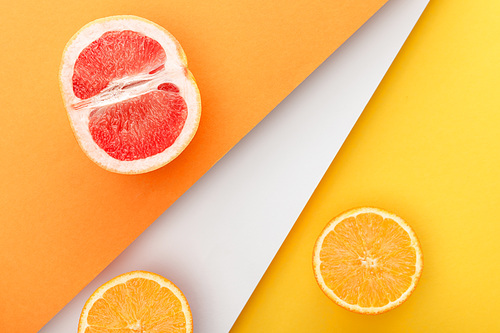 Top view of citrus halves on yellow, orange and white background