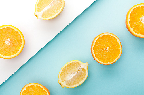 Top view of cut oranges and lemon halves on blue and white background