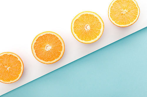 Top view of cut oranges on white and blue background