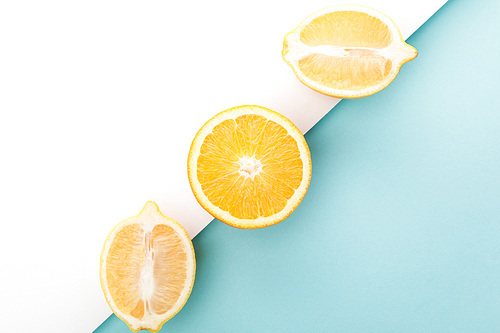 Top view of oranges half and lemon halves on white and blue background