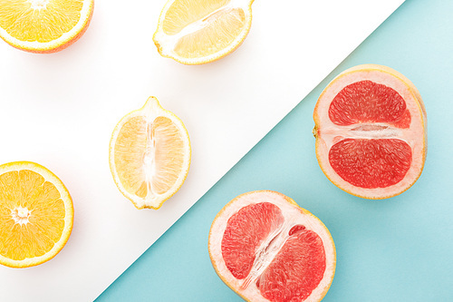 Top view of orange, lemon, grapefruit halves on blue and white background