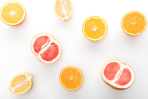 Top view of cut oranges, lemon, grapefruit halves on white background