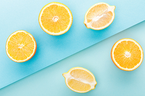 Top view of cut oranges and lemon halves on blue background