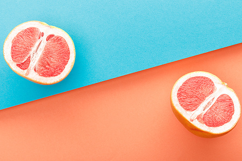 Top view of grapefruit halves on blue and orange background