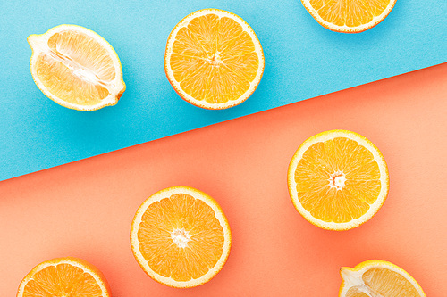 Top view of cut oranges and lemon halves on blue and orange background