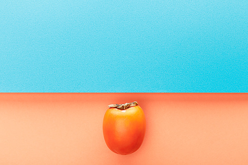 Top view of persimmon on blue and orange background