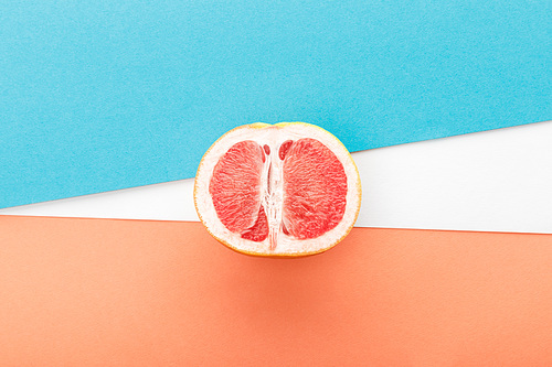Top view of grapefruit half on blue, orange and white background