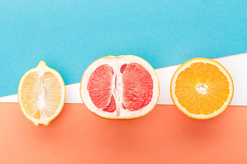 Top view of fruits halves on blue, orange and white background