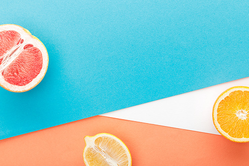 Top view of citrus fruits halves on blue, orange and white background