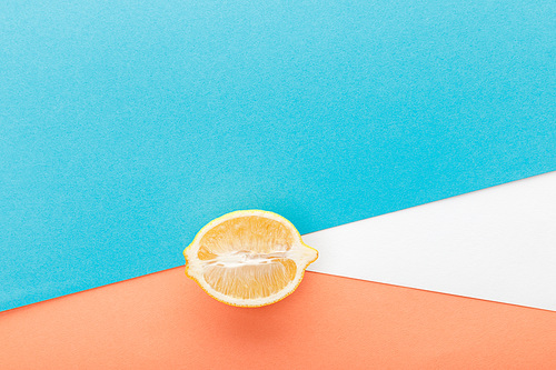 Top view of lemon half on blue, orange and white background