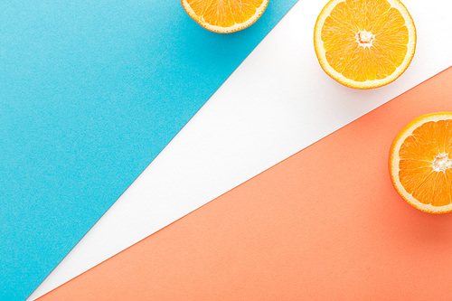 Top view of citrus fruit halves on blue, orange and white background